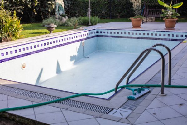 Swimming pool that is almost empty with dirty water end of the summer season